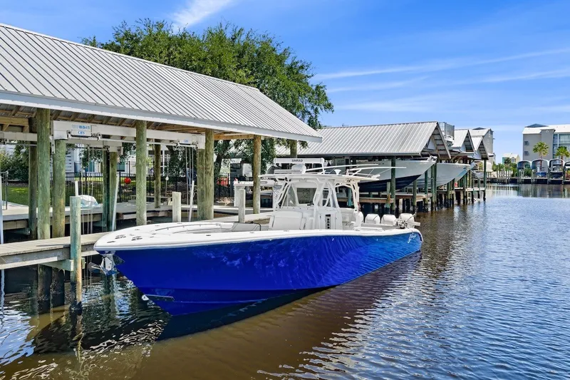Slide: The Image of 2013 Yellowfin 39 Offshore boat docked in a marina with blue hull and white deck. - 14