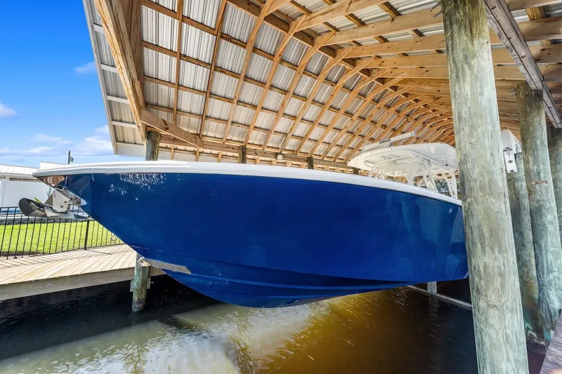 Slide: The Image of 2013 Yellowfin 39 Offshore boat in covered dock, vibrant blue hull. - 73