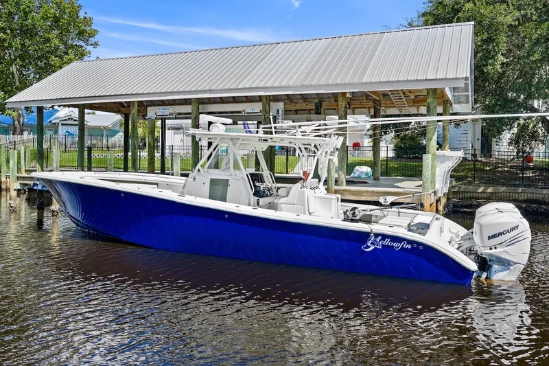 Slide: The Image of 2013 Yellowfin 39 Offshore boat docked, featuring a sleek blue hull and Mercury engines. - 6