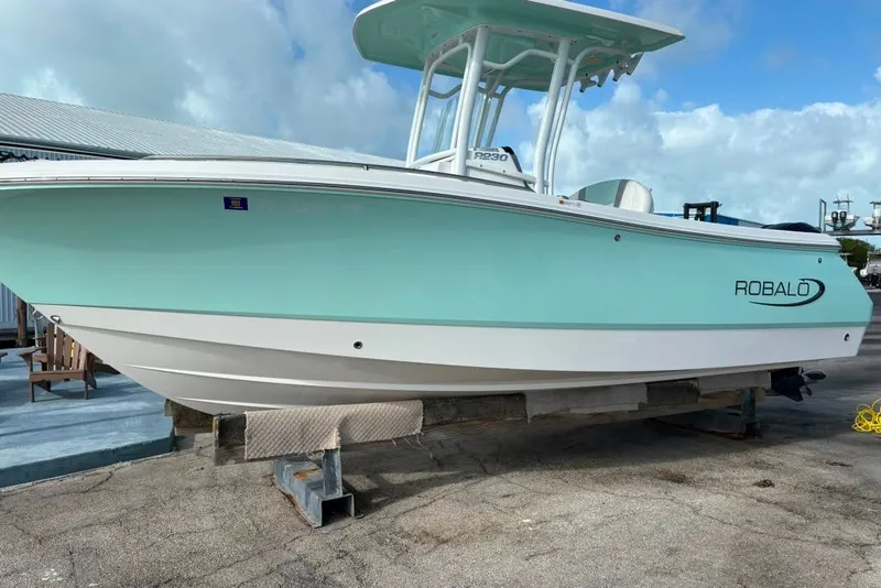 The Image of 2023 Robalo R230 Center Console boat on display, featuring a sleek design and mint green hull. - 0