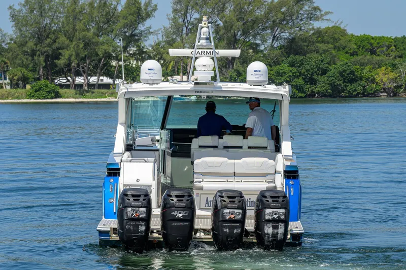 Slide: The Image of 2019 Formula 430 Super Sport Crossover boat with multiple outboard engines on a calm waterway. - 64