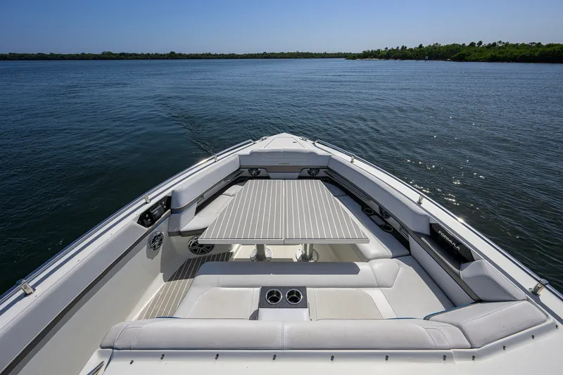 Slide: The Image of 2019 Formula 430 Super Sport Crossover boat interior with seating and table on calm water. - 50