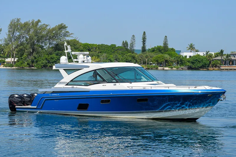 Slide: The Image of 2019 Formula 430 Super Sport Crossover boat on calm water, surrounded by lush greenery. - 55