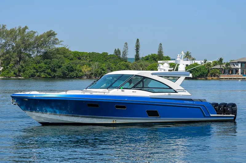 Slide: The Image of 2019 Formula 430 Super Sport Crossover boat on calm water, surrounded by lush greenery. - 58
