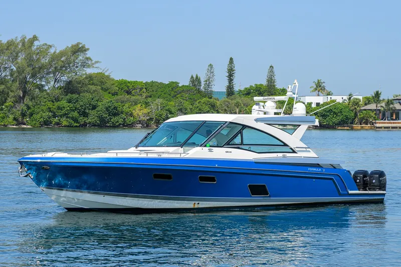 Slide: The Image of 2019 Formula 430 Super Sport Crossover boat on calm water, surrounded by lush greenery. - 57