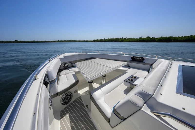 Slide: The Image of 2019 Formula 430 Super Sport Crossover boat interior with seating and table on calm water. - 49