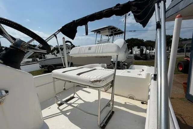 Slide: The Image of 2011 Carolina Skiff JVX18CC boat interior with seating and steering wheel, parked outdoors. - 10