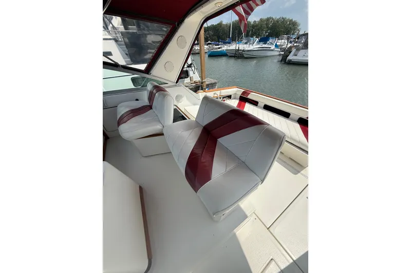 Slide: The Image of 1989 Sea Ray 340 Sundancer interior with white and red seating, docked at marina. - 14
