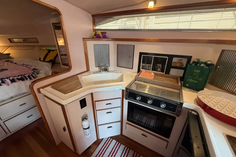 Slide: The Image of 1989 Sea Ray 340 Sundancer interior kitchen with stove, sink, and storage cabinets. - 27
