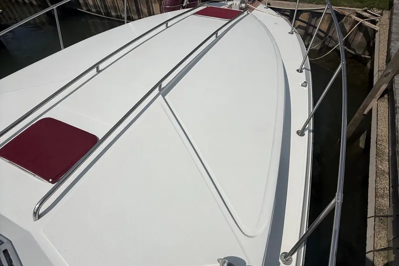 Slide: The Image of 1989 Sea Ray 340 Sundancer boat deck with stainless steel railings and maroon cushions. - 9