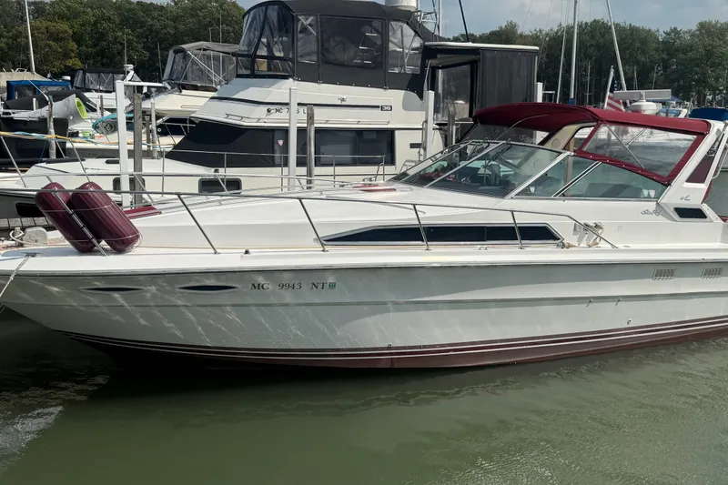 Slide: The Image of 1989 Sea Ray 340 Sundancer docked at marina, featuring sleek white design and maroon accents. - 3