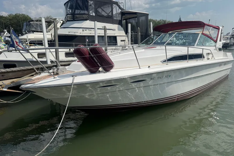 The Image of 1989 Sea Ray 340 Sundancer docked at marina, featuring sleek design and red canopy. - 1