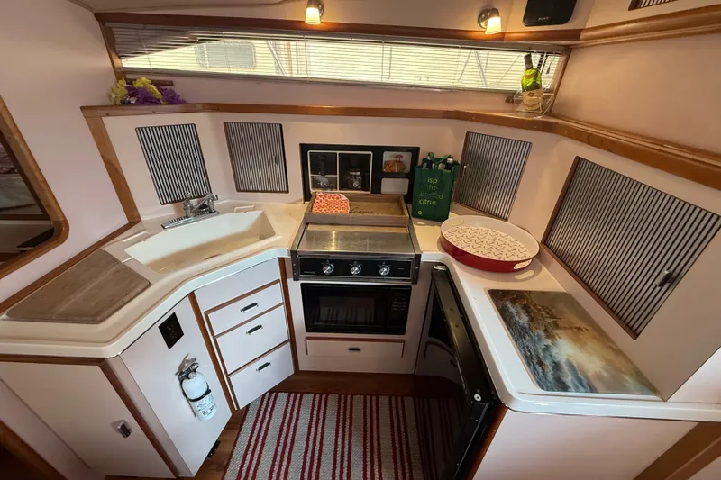 Slide: The Image of 1989 Sea Ray 340 Sundancer kitchen with stove, sink, and striped rug. - 26