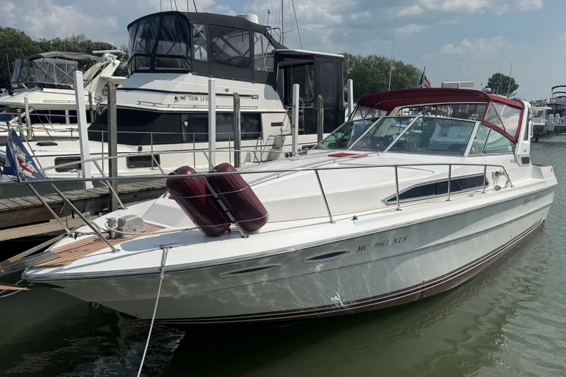 Slide: The Image of 1989 Sea Ray 340 Sundancer docked at marina, featuring sleek design and red canopy. - 2