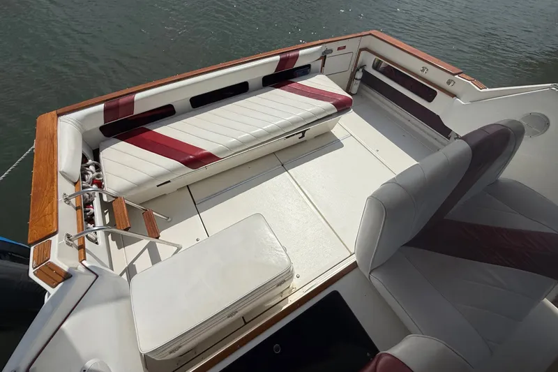 Slide: The Image of 1989 Sea Ray 340 Sundancer boat interior with white and red seating, docked on water. - 12
