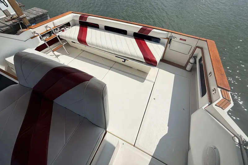 Slide: The Image of 1989 Sea Ray 340 Sundancer boat interior with white and red seating, docked by water. - 13
