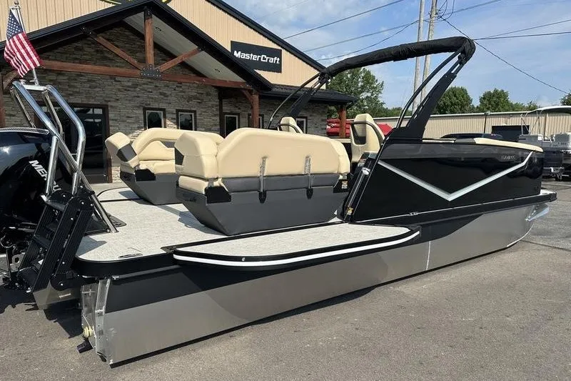 Slide: The Image of 2026 Flamingo Rove 24' pontoon boat with beige seating, parked outside MasterCraft building. - 18