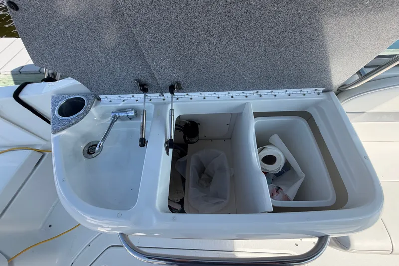 Slide: The Image of 2004 Formula 260 Bowrider boat sink and storage compartments with open lid. - 30