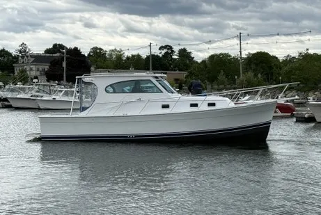 Slide: The Image of A white 1999 Mainship Pilot 30 Sedan boat sits calmly in a harbor's water. - 28