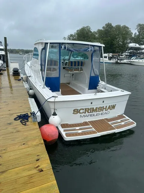 Slide: The Image of A 1999 Mainship Pilot 30 Sedan docked. It features an open rear and blue covers. - 0