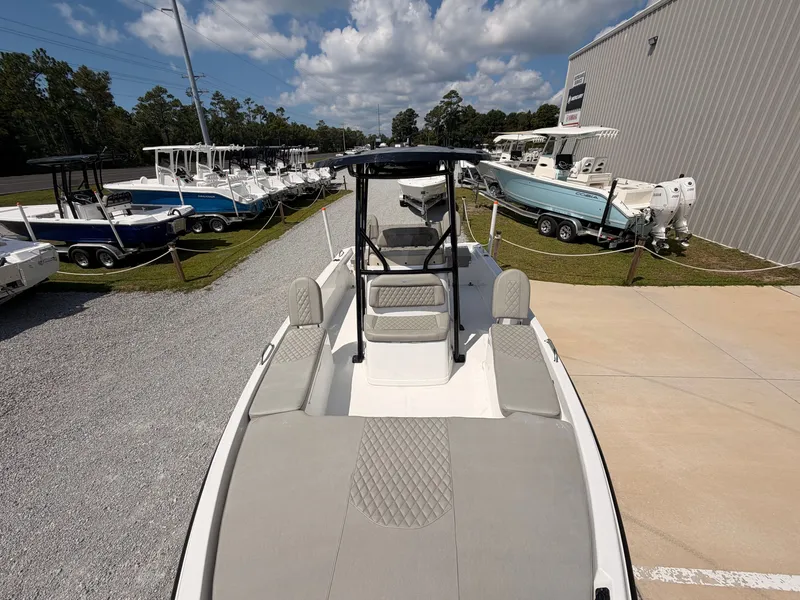 Slide: The Image of The image shows a 2027 Savannah 210X boat on a lot. It features modern design with gray upholstery and a black T-top. Other boats are visible in the background. - 11
