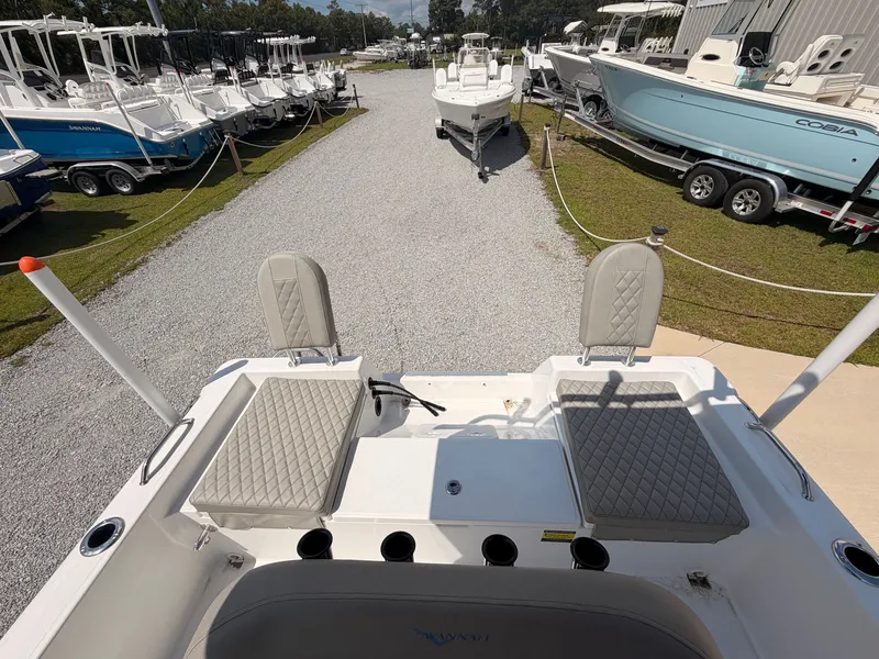 Slide: The Image of The image shows the stern of a 2027 Savannah 210X boat, surrounded by other boats on a gravel lot. - 13