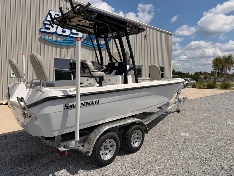 Slide: The Image of A white 2027 Savannah 210X boat on a trailer in front of a building. - 1