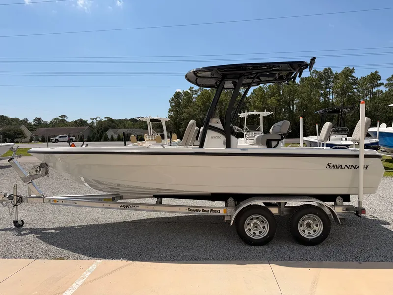 Slide: The Image of The image shows a 2027 Savannah 210X boat on a trailer, surrounded by trees. - 4