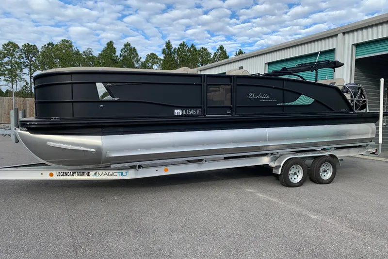 Slide: The Image of 2022 Barletta LUSSO 25U pontoon boat on trailer, parked outdoors. - 1