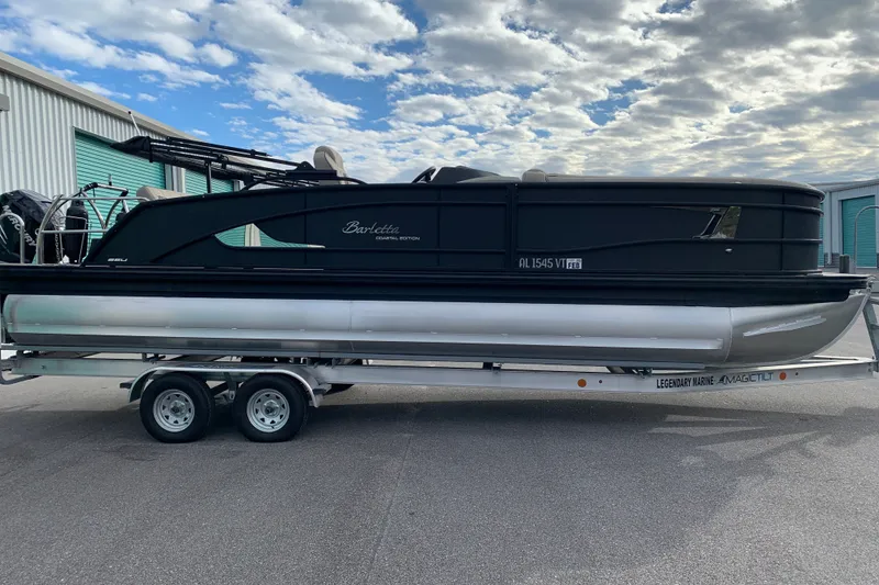 Slide: The Image of 2022 Barletta LUSSO 25U pontoon boat on trailer, parked outdoors under cloudy sky. - 2
