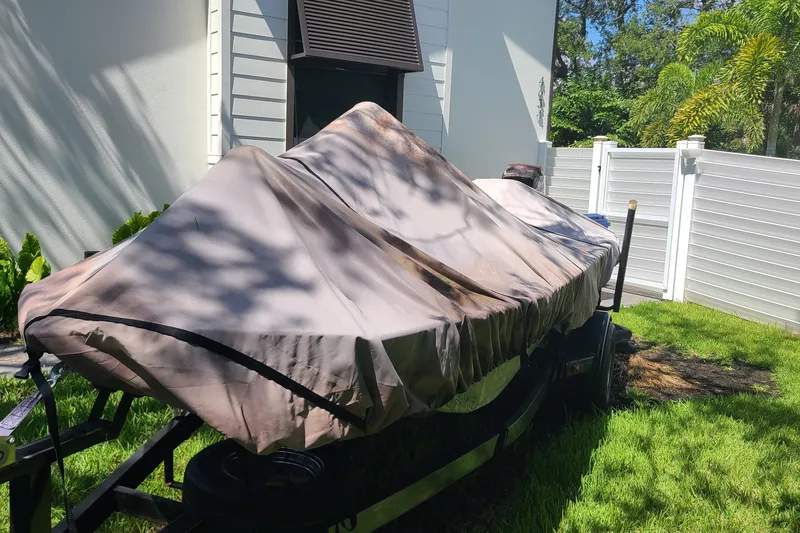 Slide: The Image of Covered War Eagle 761 Blackhawk boat from 2000, parked on grass beside a white fence. - 14