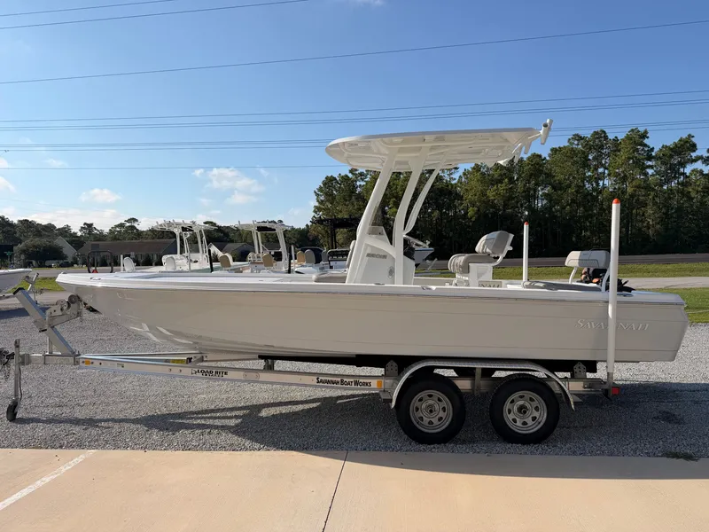 Slide: The Image of A 2027 Savannah 220 IS boat on a trailer, surrounded by trees and other boats. - 4