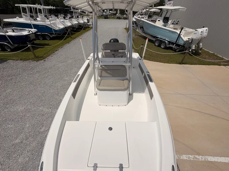 Slide: The Image of A modern center console boat with white seating and a shade canopy, parked on a lot. - 12