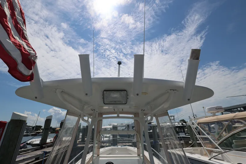 Slide: The Image of 1999 Regulator 26 Forward Seating boat with T-top and American flag, docked under blue sky. - 29