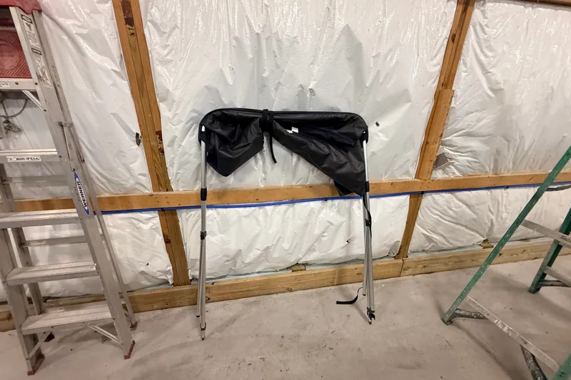 Slide: The Image of Folded Zodiac Yachtline 2 Deluxe 340 canopy against insulated wall, flanked by ladders. - 16