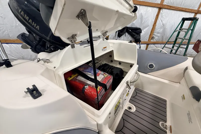 Slide: The Image of 2013 Zodiac Yachtline 2 Deluxe 340 storage compartment with Yamaha engine in a garage setting. - 9