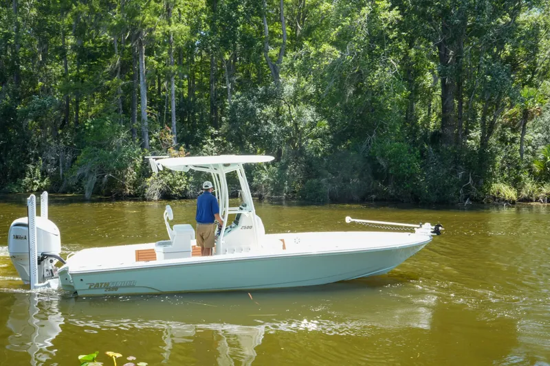Slide: The Image of 2026 Pathfinder 2500 Tournament boat cruising on a forest-lined river. - 12