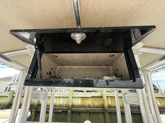Slide: The Image of An open storage compartment on a 2022 Ribcraft 6.5 boat, with metal frame and dock in the background. - 7