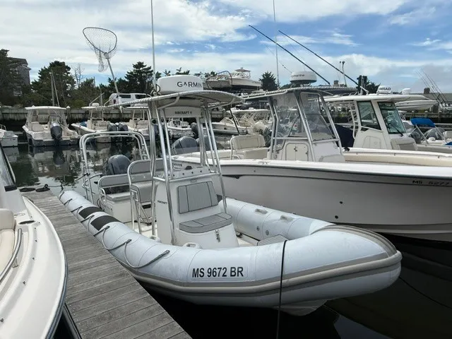 Slide: The Image of A 2022 Ribcraft 6.5 is docked in a marina, surrounded by other boats. - 2