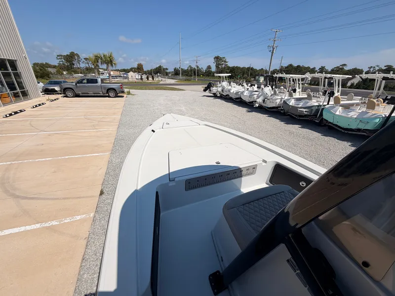 Slide: The Image of A 2027 Savannah 220 IS boat is parked on a lot beside other boats and vehicles. - 8