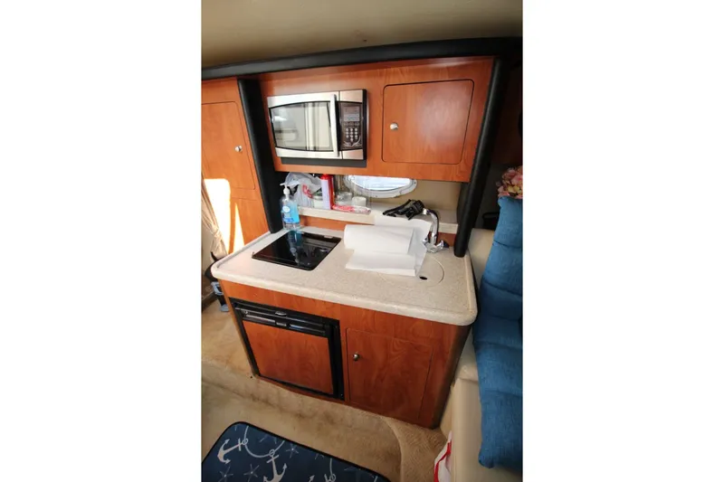Slide: The Image of 2008 Rinker 280 Express Cruiser interior kitchen with microwave, stove, and sink. - 18