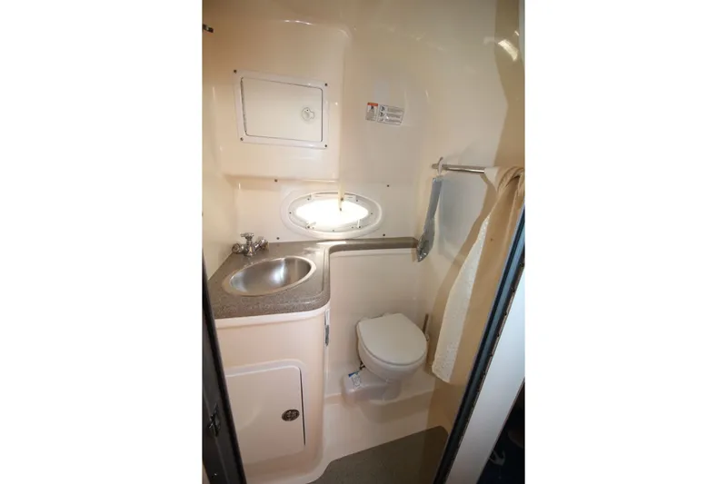 Slide: The Image of 2008 Rinker 280 Express Cruiser bathroom with sink, toilet, and porthole window. - 19