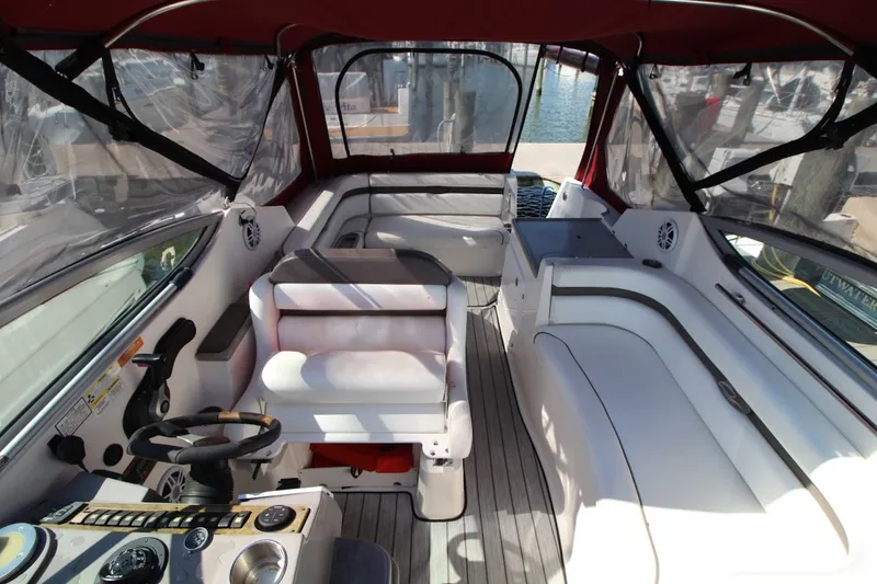 Slide: The Image of 2008 Rinker 280 Express Cruiser interior with seating and helm, featuring red canopy. - 10
