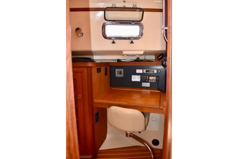Slide: The Image of Navigation station inside 2004 Island Packet 370 sailboat, featuring wooden cabinetry and control panel. - 17