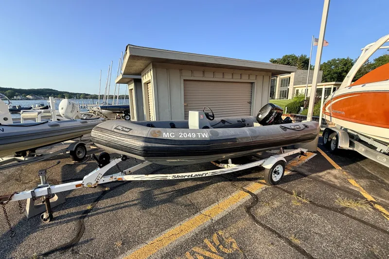 The Image of 2014 Zodiac Milpro SR 4.70 inflatable boat on trailer, parked near marina. - 1