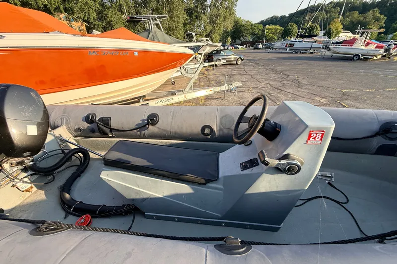 Slide: The Image of 2014 Zodiac Milpro SR 4.70 inflatable boat with steering console, parked near other boats. - 14