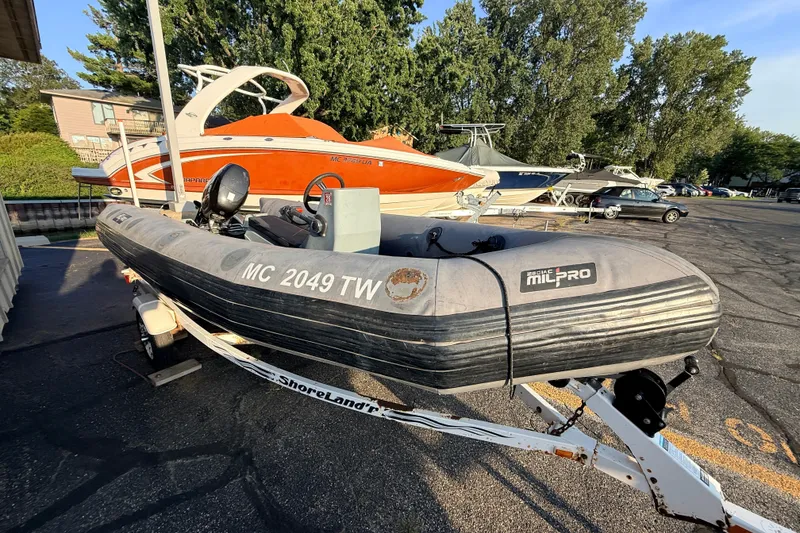 Slide: The Image of 2014 Zodiac Milpro SR 4.70 inflatable boat on trailer, parked in marina lot. - 15