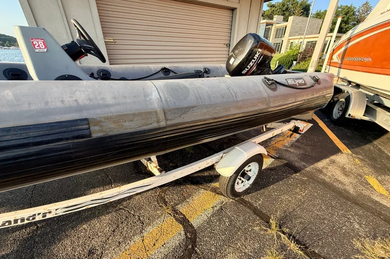 Slide: The Image of 2014 Zodiac Milpro SR 4.70 inflatable boat on trailer, parked outdoors. - 24