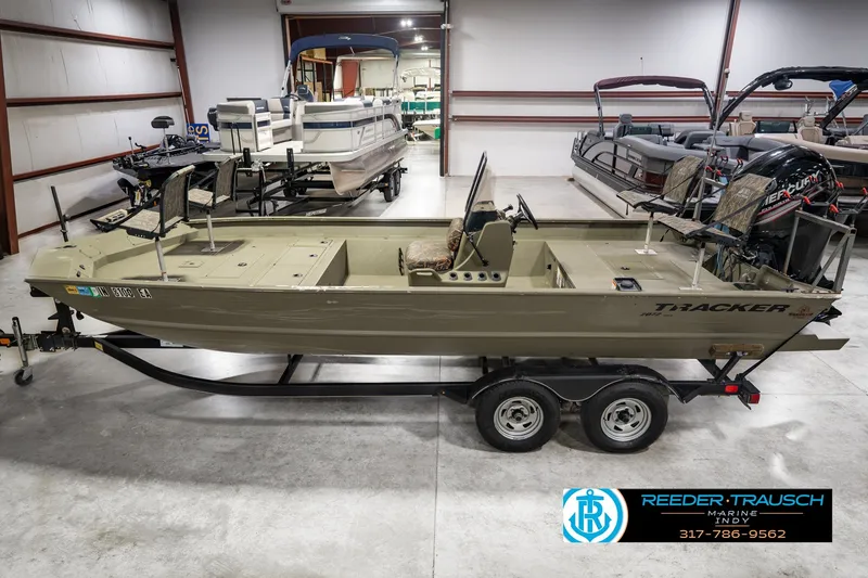 The Image of 2018 Tracker Grizzly 2072 CC boat on trailer in showroom, featuring camo seats. - 0