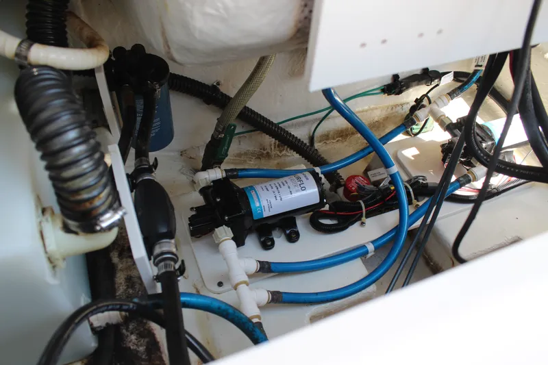 Slide: The Image of A view inside the engine compartment of a 2015 Robalo R222 Center Console boat with various hoses and a pump. - 23